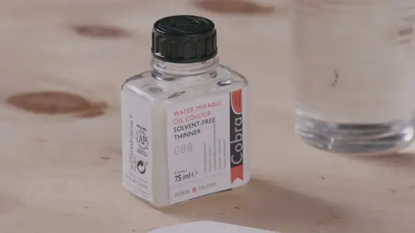 Bouteille de diluant Cobra pour peinture acrylique à base d'eau, sur fond de bois.